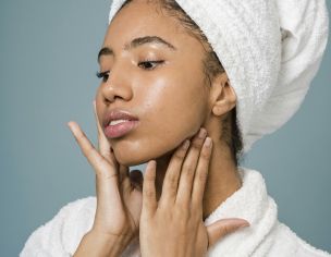 Young woman in a spa setting applying skincare with a fresh clean look.